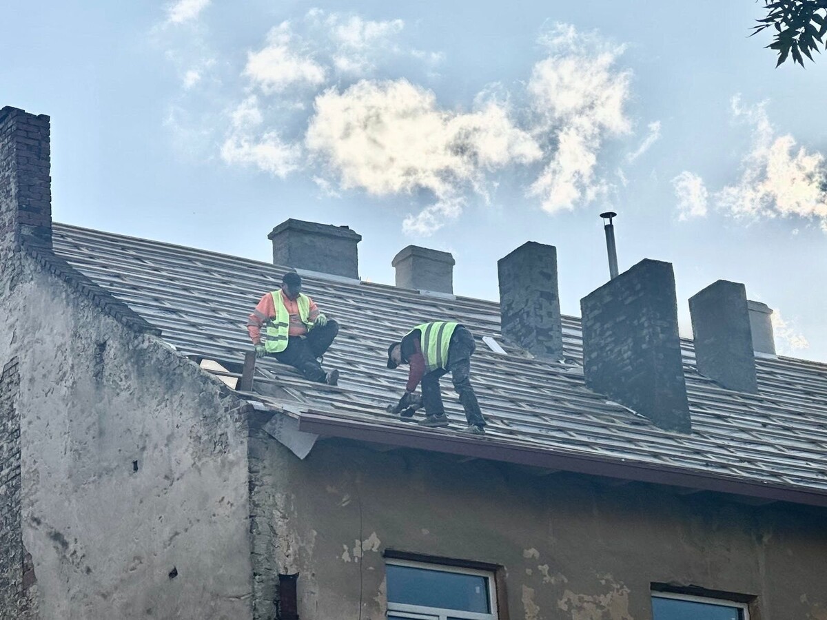 два чоловіки на даху будинку на вул. Шараневича, 8 працюють над відновленням покрівлі